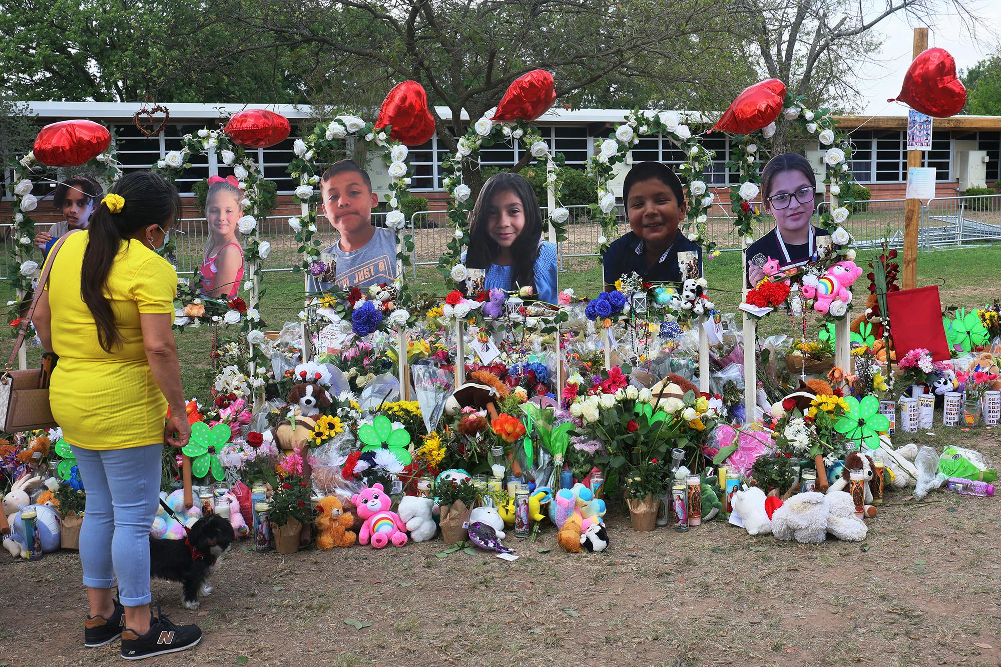 A woman looks down at a memorial for the 19 children and two adults killed on May 24th during a mass shooting at Robb Elementary School on May 30, 2022, in Uvalde, Texas.