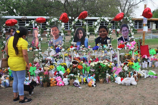 A woman looks down at a memorial for the 19 children and two adults killed on May 24th during a mass shooting at Robb Elementary School on May 30, 2022, in Uvalde, Texas.