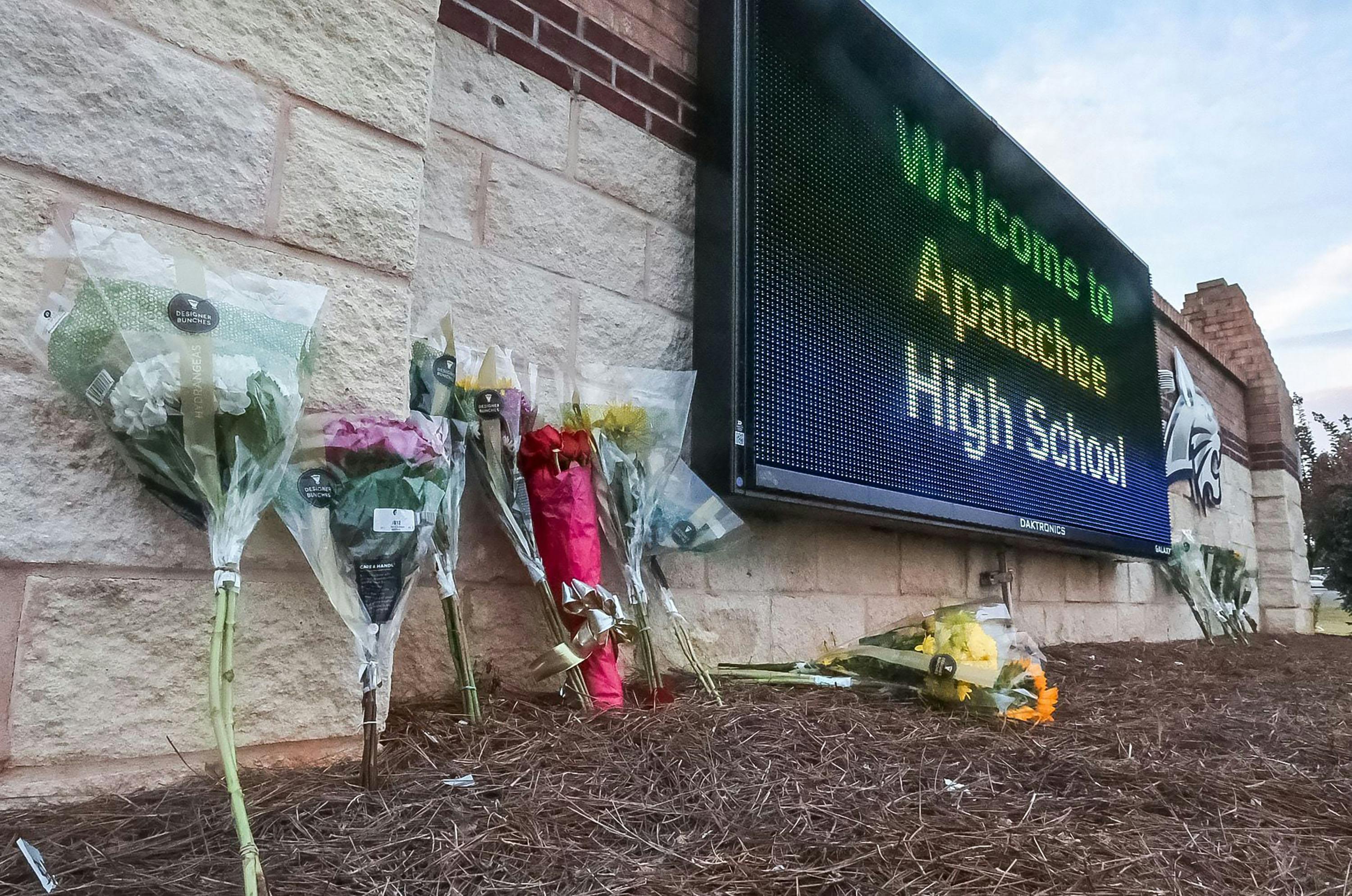 Flowers are placed at the foot of the welcome sign to Apalachee High School for a makeshift memorial on Sept. 5, 2024.