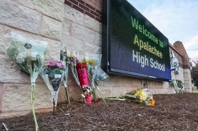 Flowers are placed at the foot of the welcome sign to Apalachee High School for a makeshift memorial on Sept. 5, 2024.