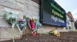 Flowers are placed at the foot of the welcome sign to Apalachee High School for a makeshift memorial on Sept. 5, 2024.