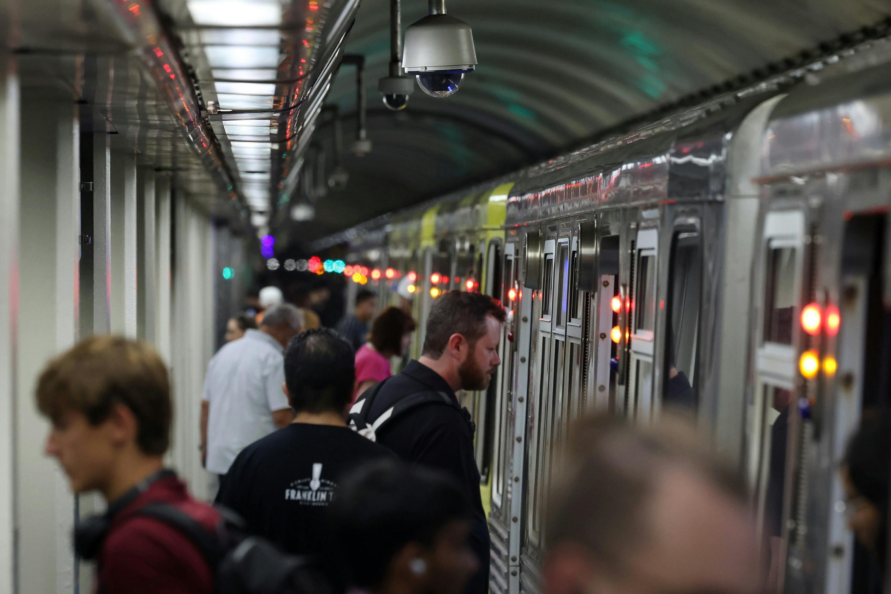 Passengers enter and exit a train under surveillance cameras at the CTA Jackson Blue Line station in Chicago on Aug. 28, 2024.