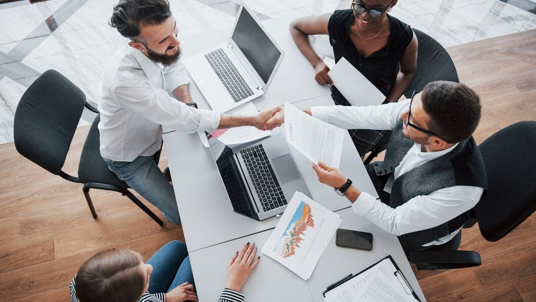 672e5a542072156e676808db Youngemployeessittingofficetableusinglaptopteamwor