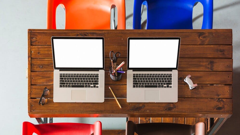 676067bfe8feecdeaa1cffa4 Twoopenlaptopswithpencilsholderwoodentablewithempt