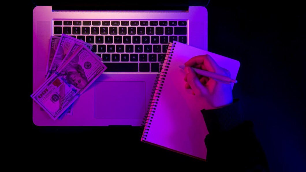 6764840bfb3927819f871dad Laptopblanknotepadpapermoneyneonlightingtopview 16