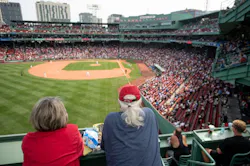 Fans watch a game from atop Fenway Park's iconic Green Monster, where preserving the ballpark's historic character remains a key consideration as security infrastructure continues to evolve.
