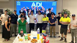 Employees at an ADI branch celebrate the company's first day of trading on the New York Stock Exchange as an independent public company, watching the exchange ceremony on a large screen.