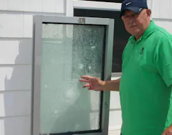 School security consultant Patrick V. Fiel Sr. demonstrates how security film can help hold shattered glass in place after gunfire, potentially delaying an attacker’s entry and providing additional time for emergency response.